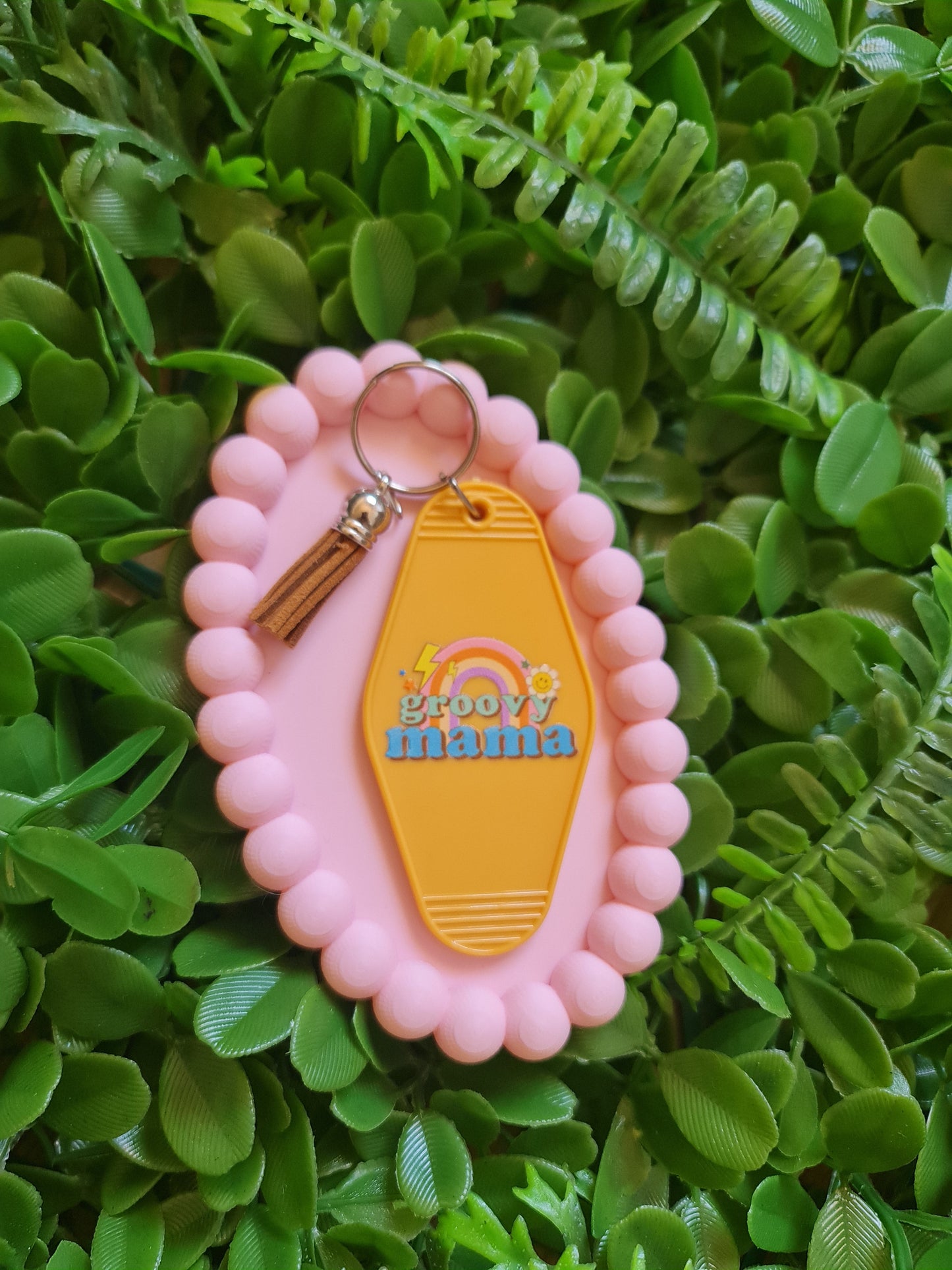 Pink keychain with a yellow tag on green leaves