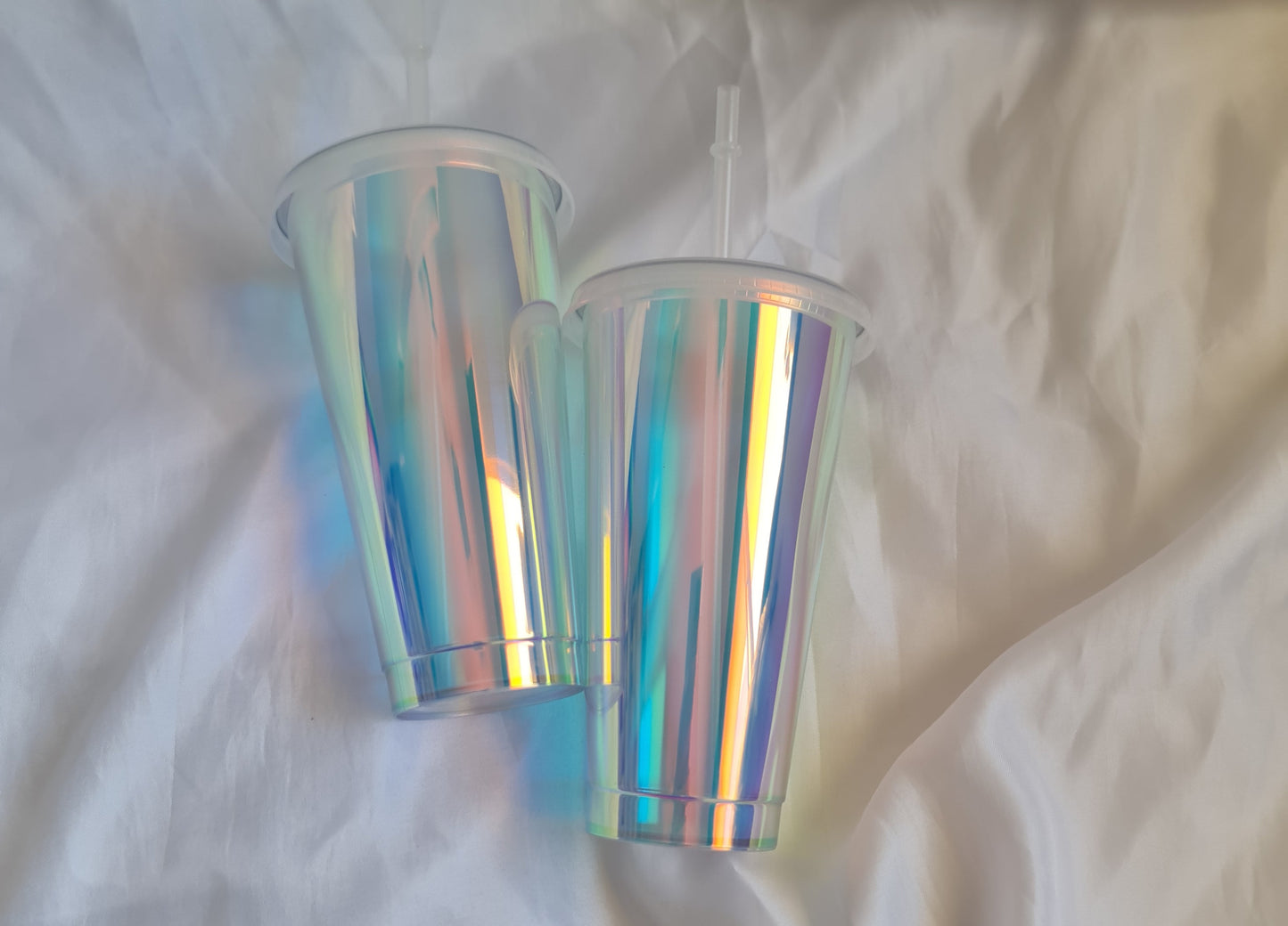 Iridescent cylindrical objects on a white fabric background