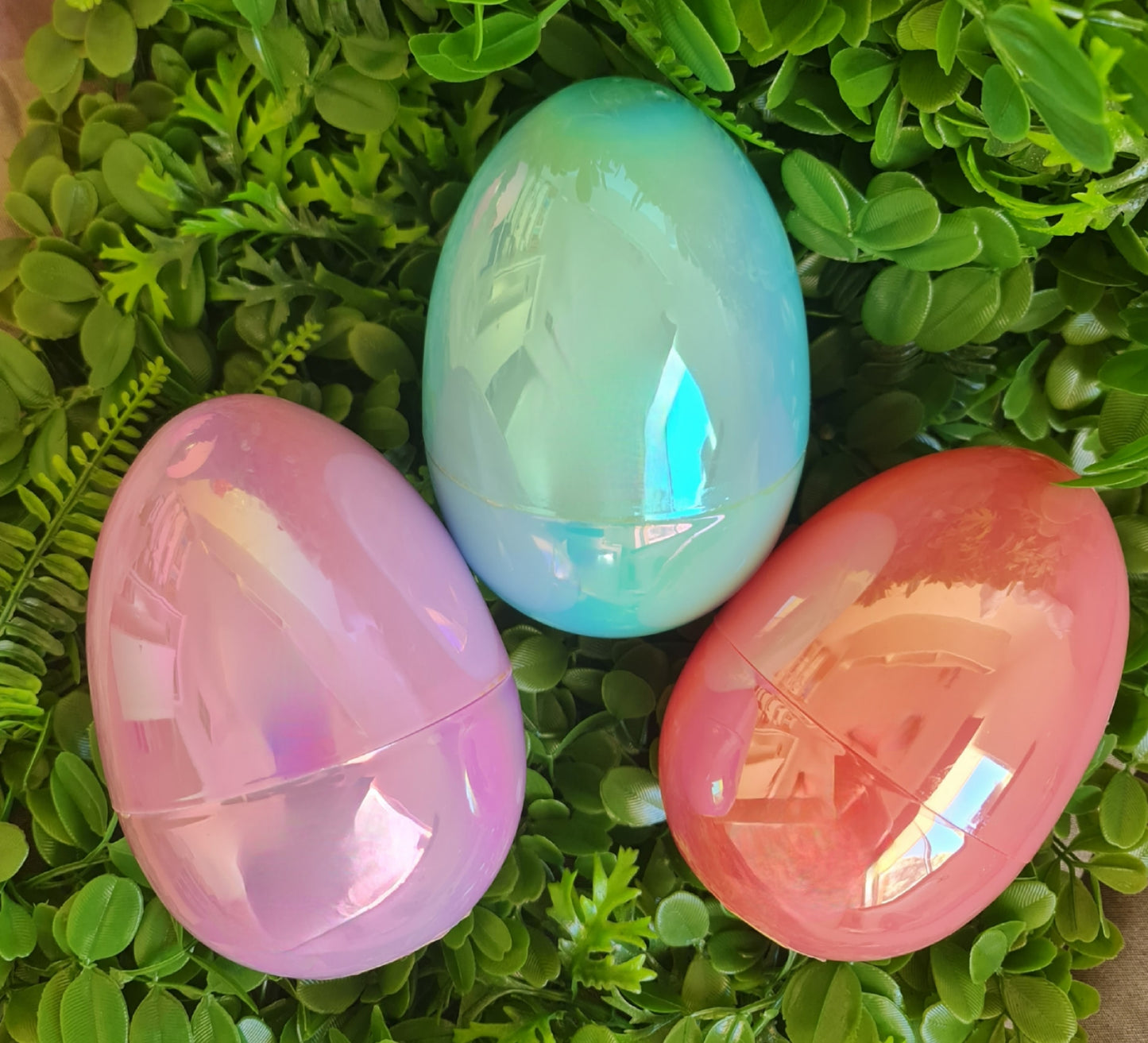 Three iridescent Easter eggs on a green leafy background
