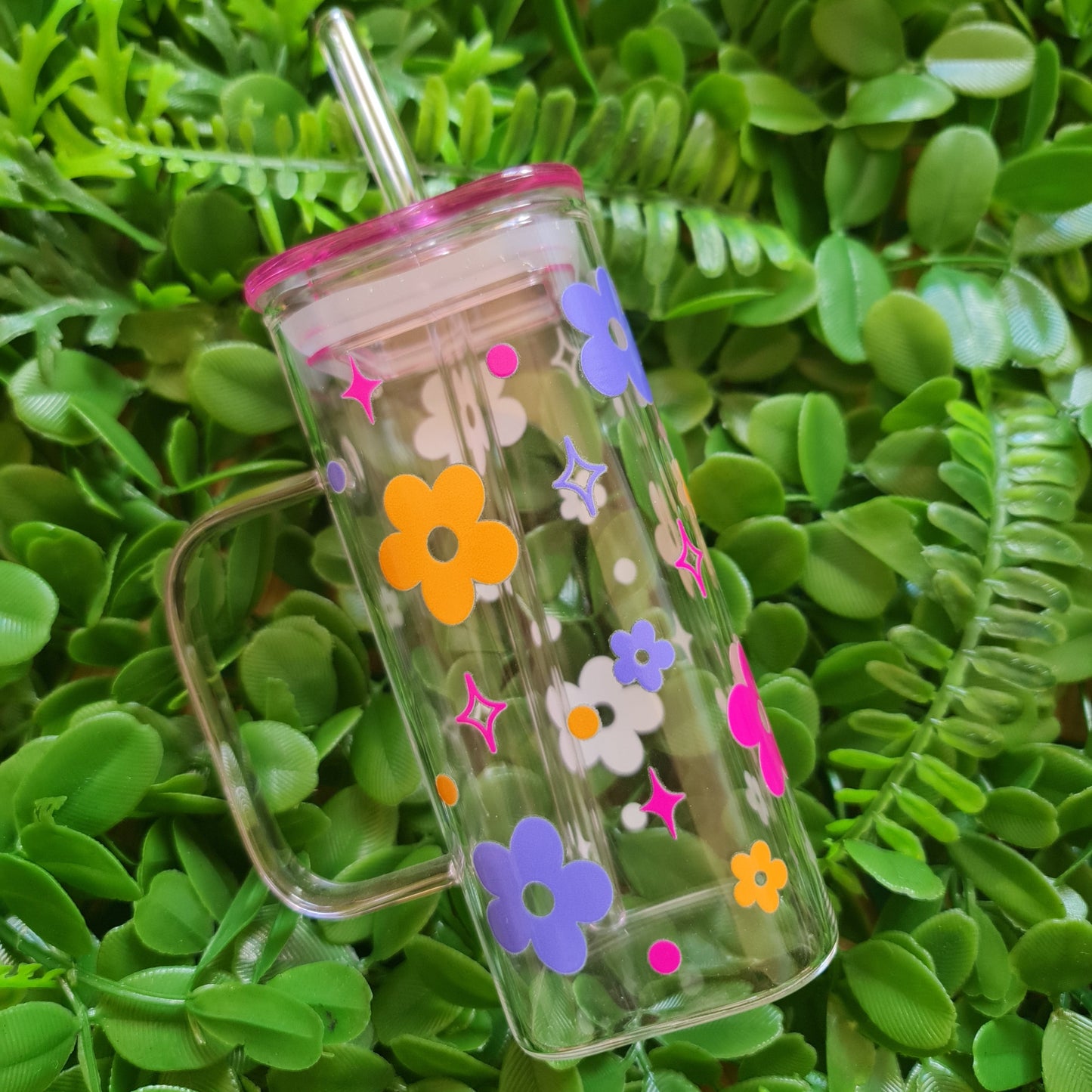 Clear straw with colorful flower designs on a green leaf background