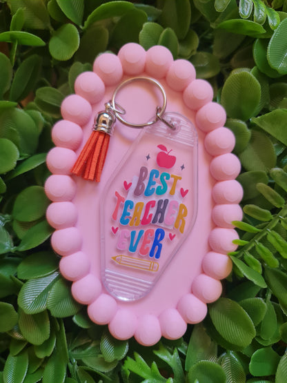 Pink keychain with 'Best Teacher Ever' sanitizer holder on green leaves