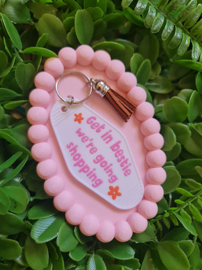 Pink keychain with a speech bubble design on a green leafy background