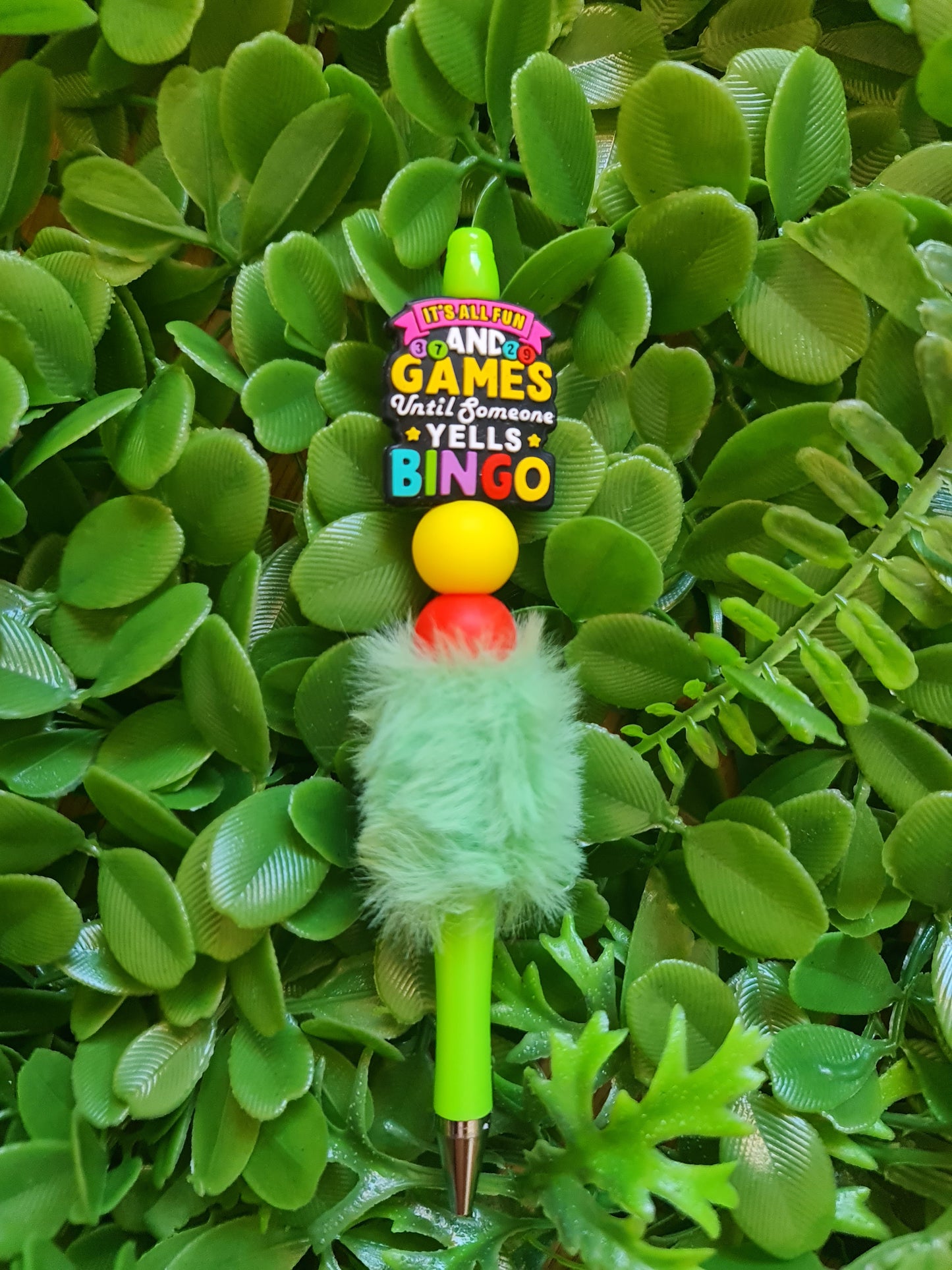 Colorful pen with fuzzy green top on a green leaf background