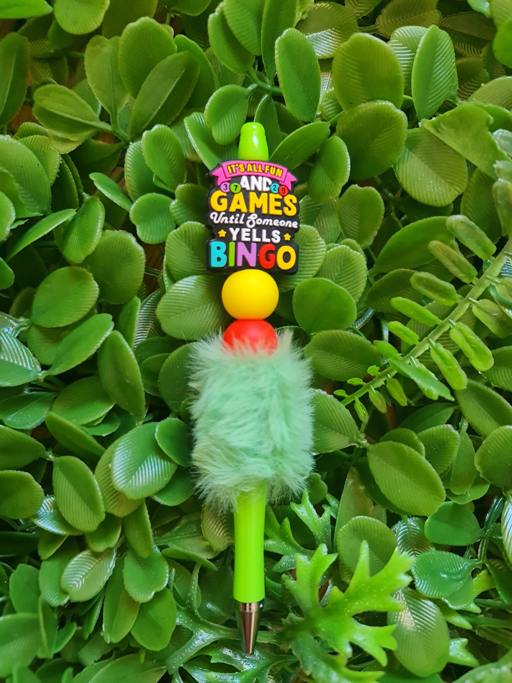 Colorful pen with fuzzy green top on a green leaf background