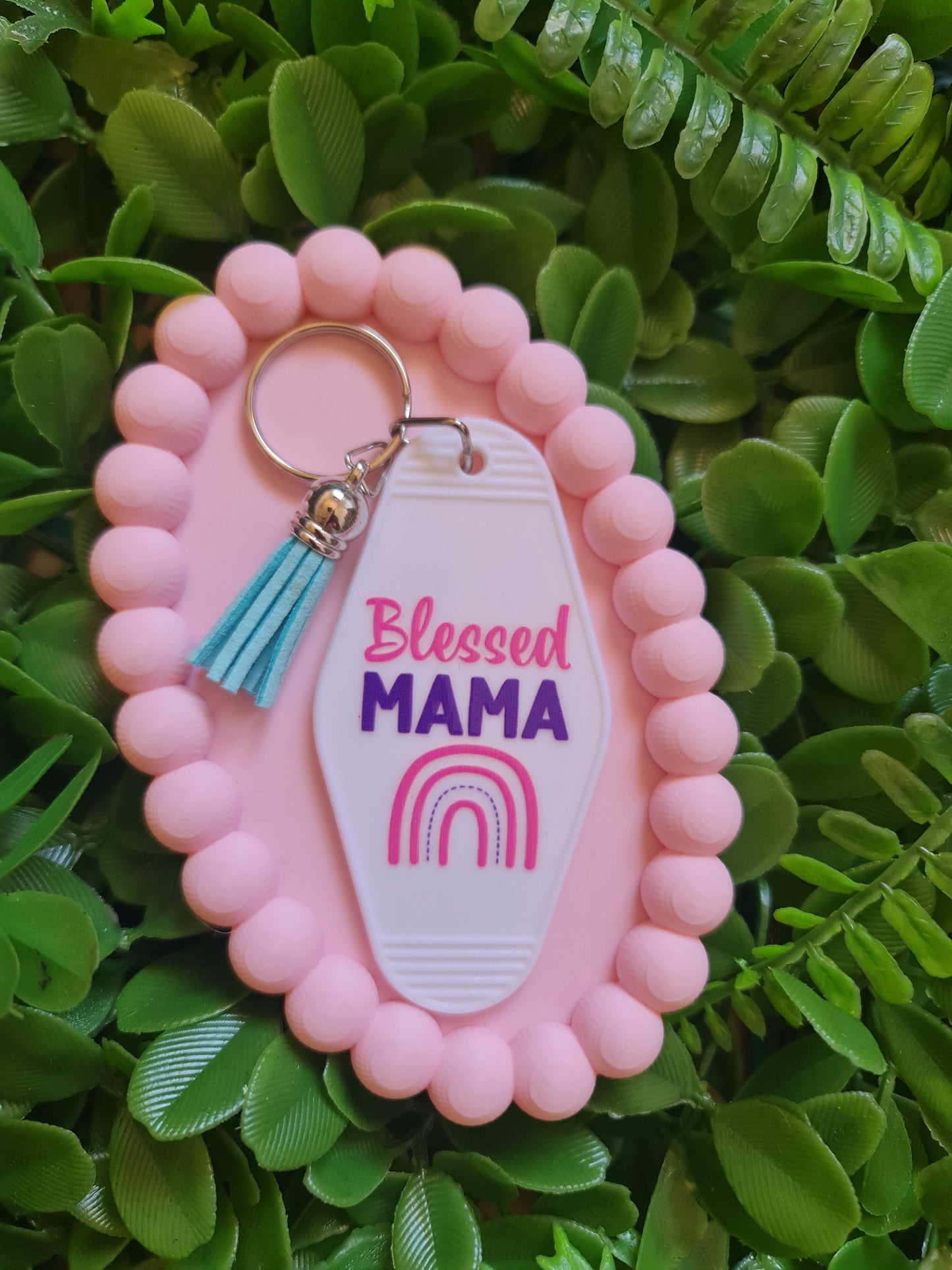 Pink keychain with 'blessed MAMA' tag on a green leafy background