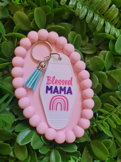 Pink keychain with 'blessed MAMA' tag on a green leafy background