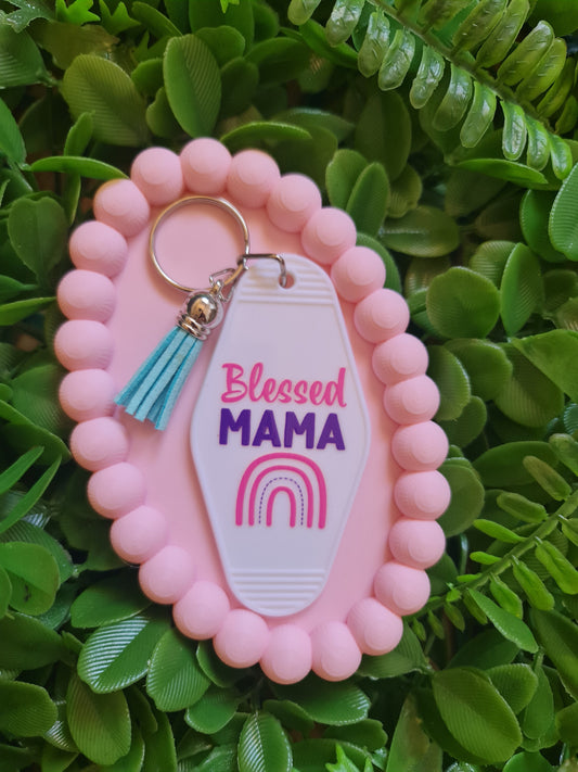 Pink keychain with 'blessed MAMA' tag on a green leafy background