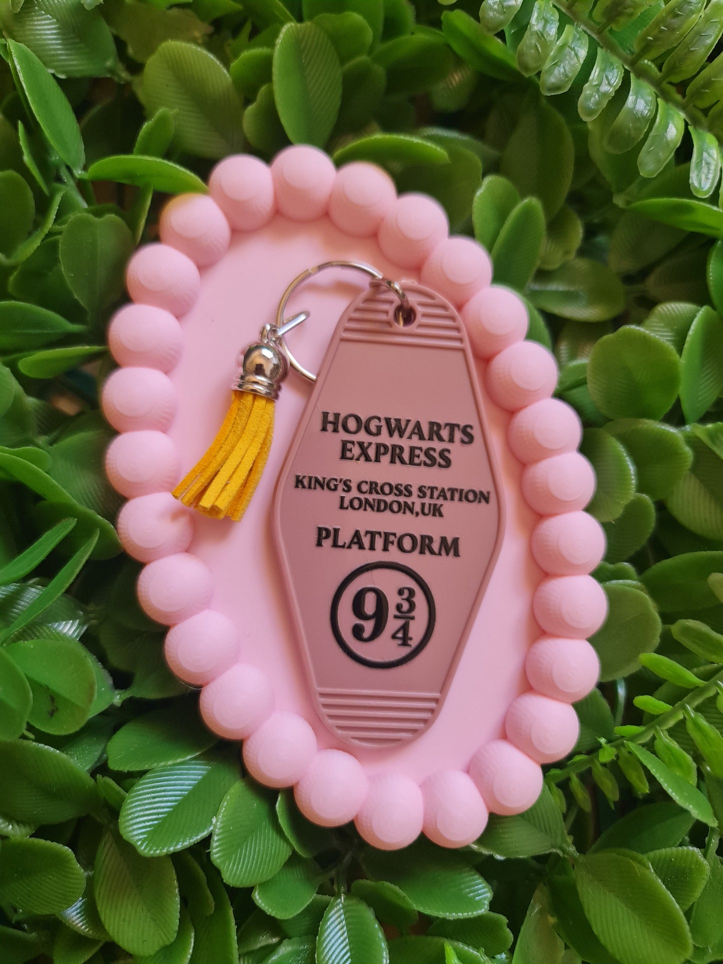 Pink keychain with 'Hogwarts Express' design on a green leafy background