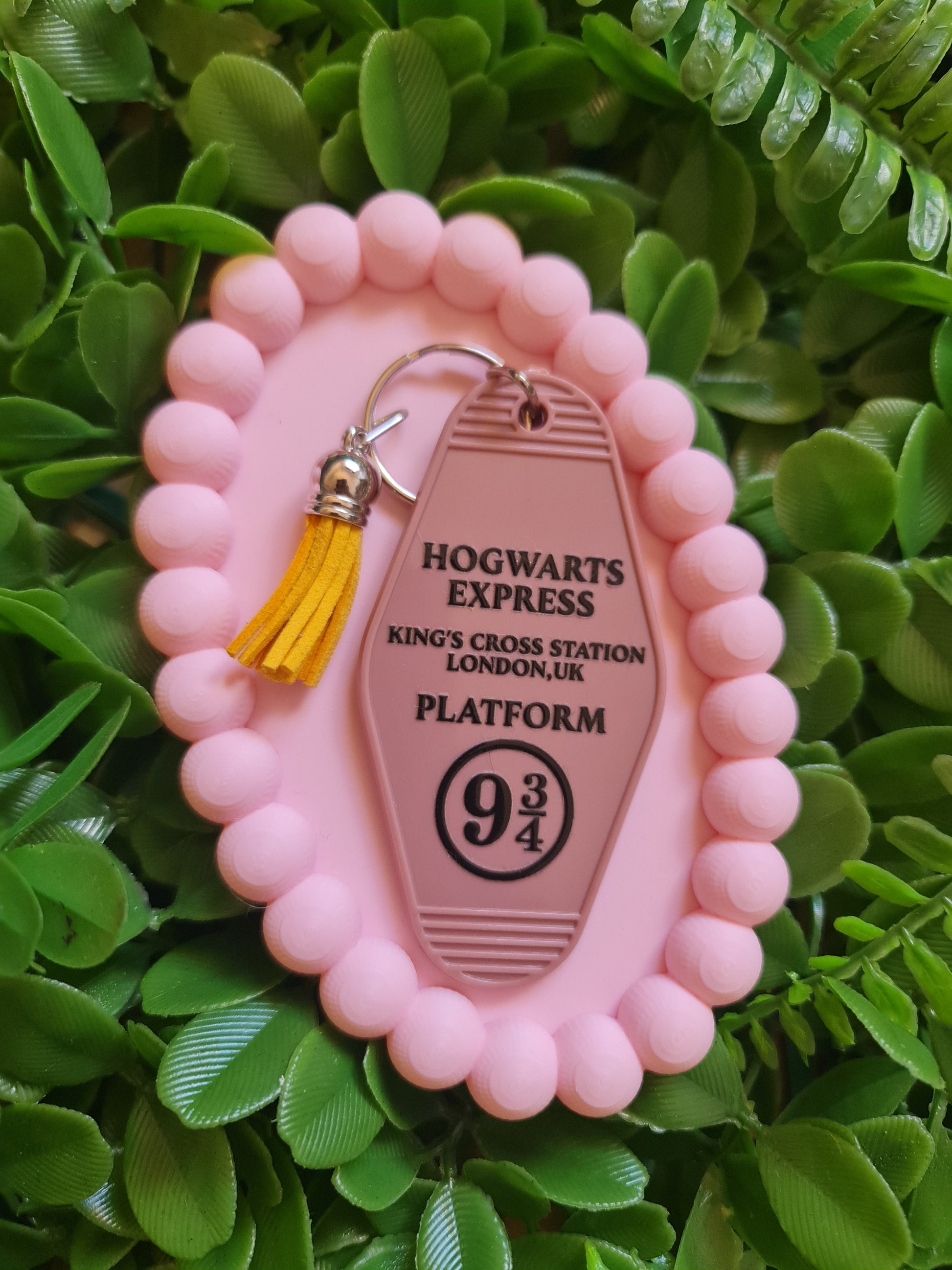 Pink keychain with 'Hogwarts Express' design on a green leafy background