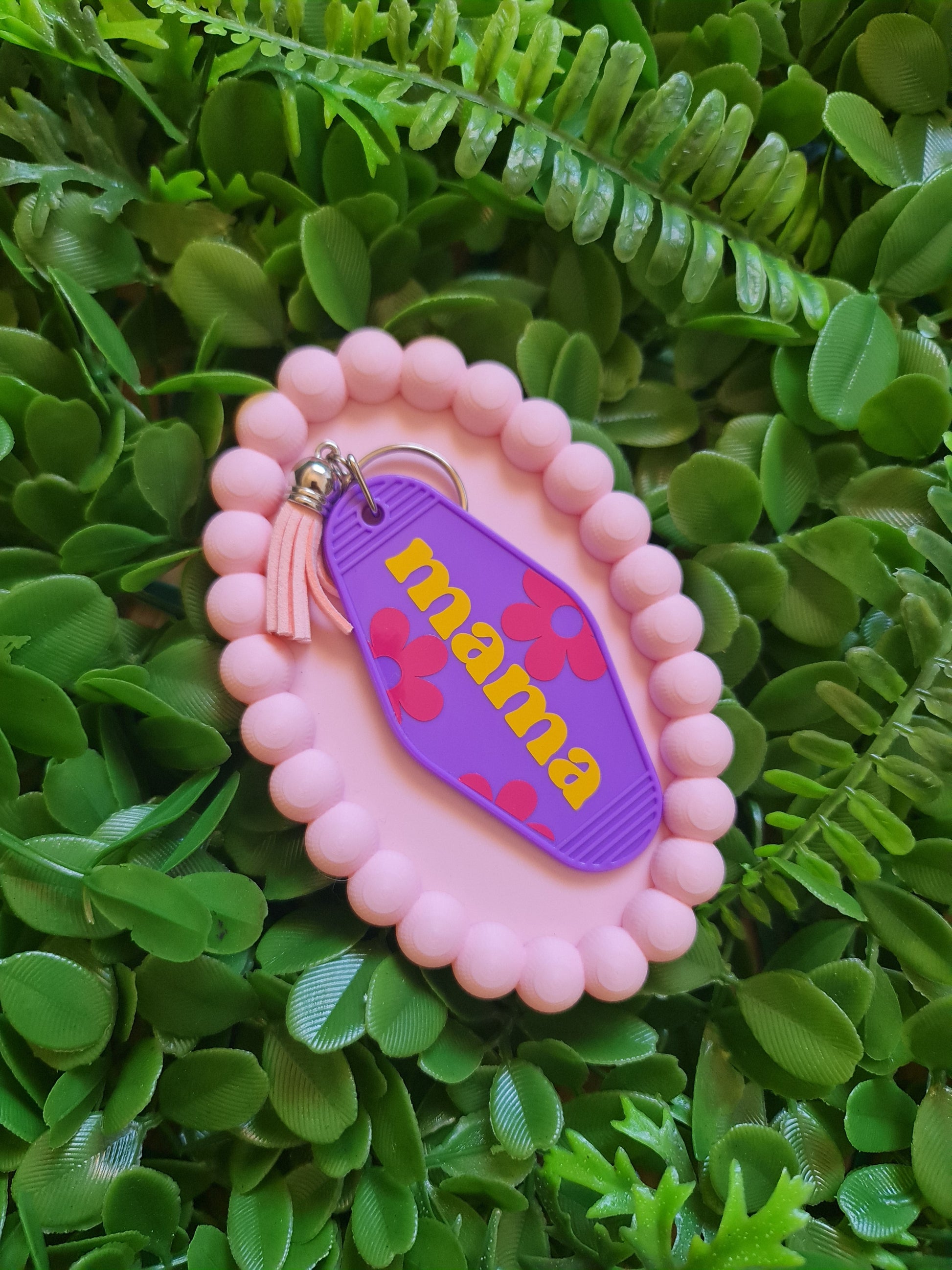 Pink 'mama' keychain on a green leafy background