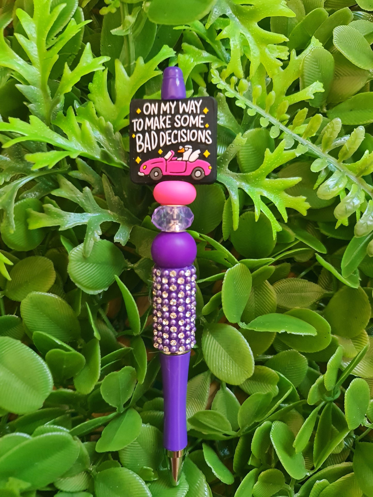 Decorative pen with purple and pink accents on a green leaf background