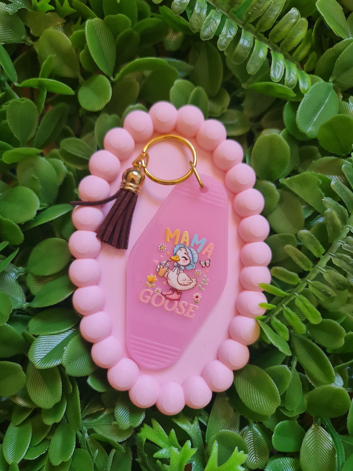Pink keychain with cartoon character on a green leafy background