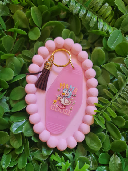 Pink keychain with cartoon character on a green leafy background