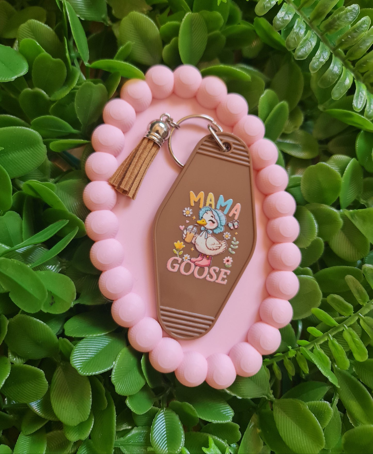 Pink keychain with a decorative tag on a green leafy background