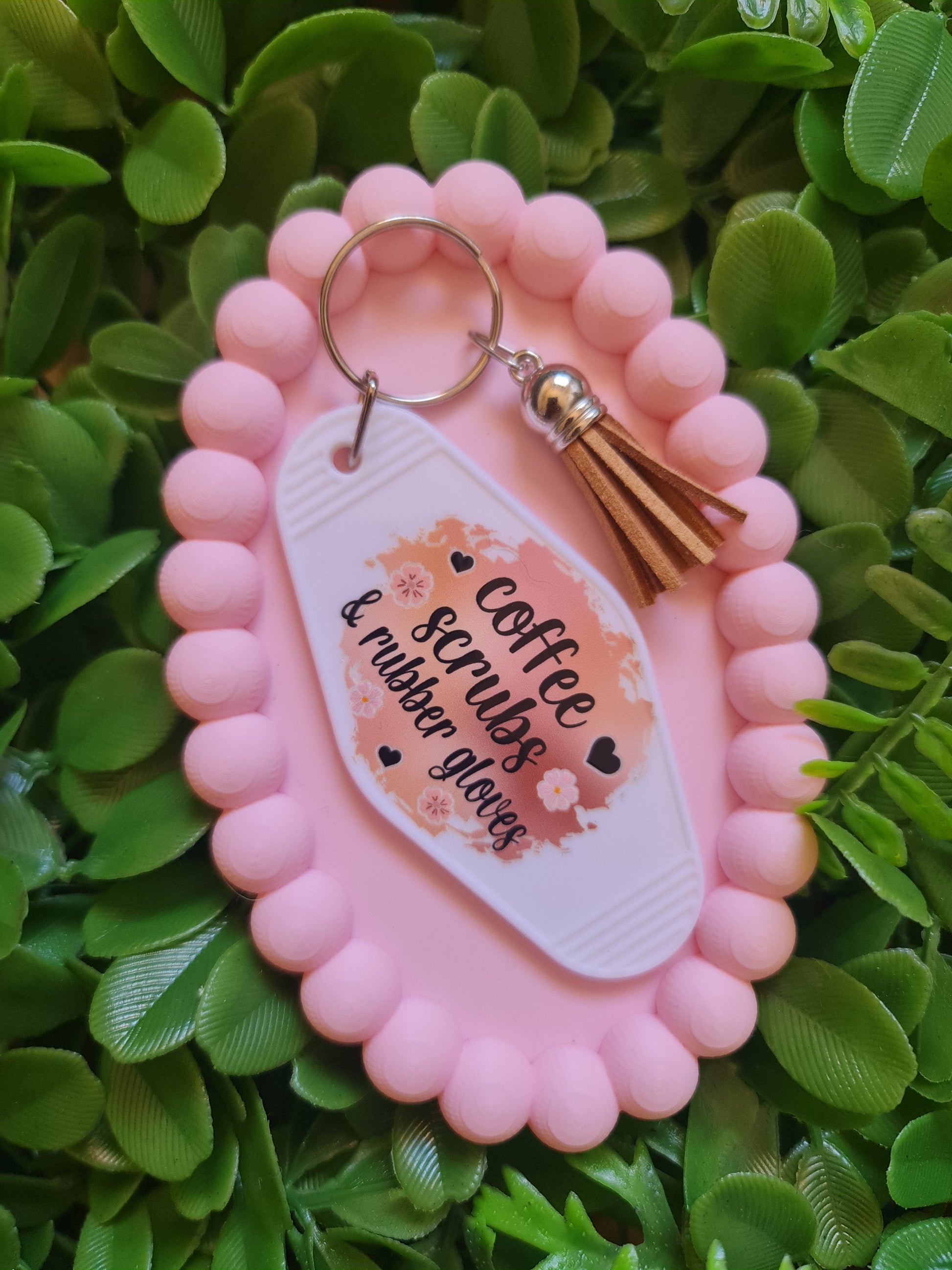 Pink keychain with a tassel on a green leafy background