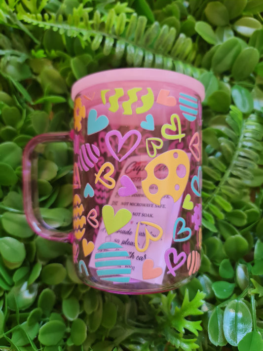 Pink container with colorful designs on a green leafy background