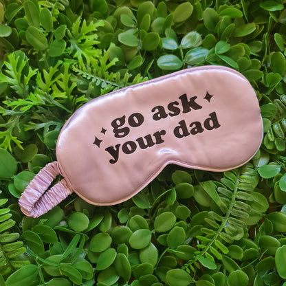 Pink sleep mask with text on a green leafy background