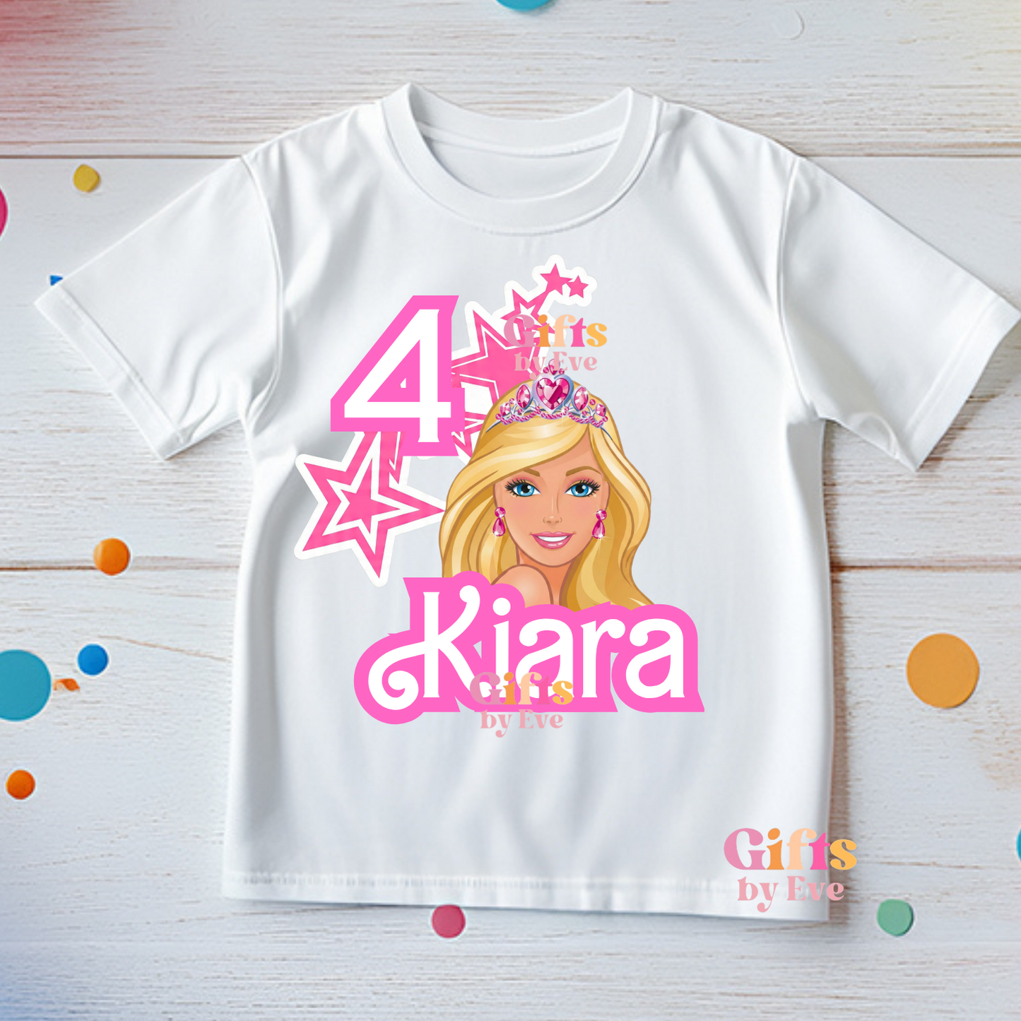 White t-shirt with a cartoon character and text on a wooden surface with colorful confetti.