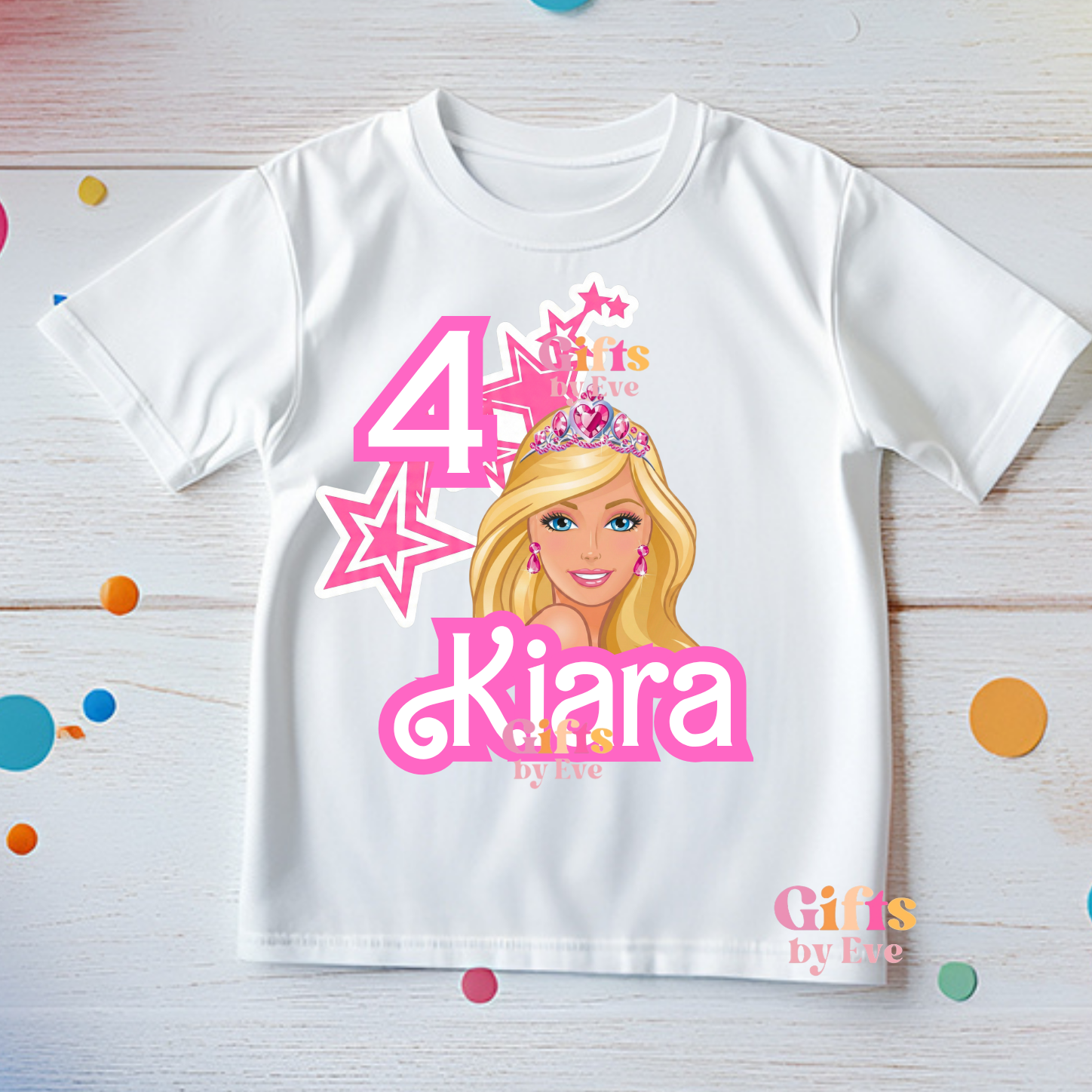 White t-shirt with a cartoon character and text on a wooden surface with colorful confetti.