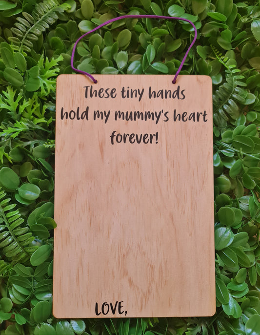 Wooden plaque with engraved text on a green leafy background