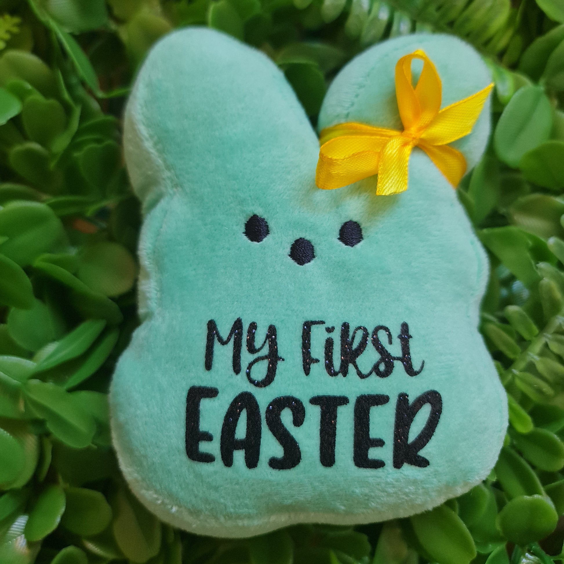 Green plush bunny with 'My First Easter' text on grass