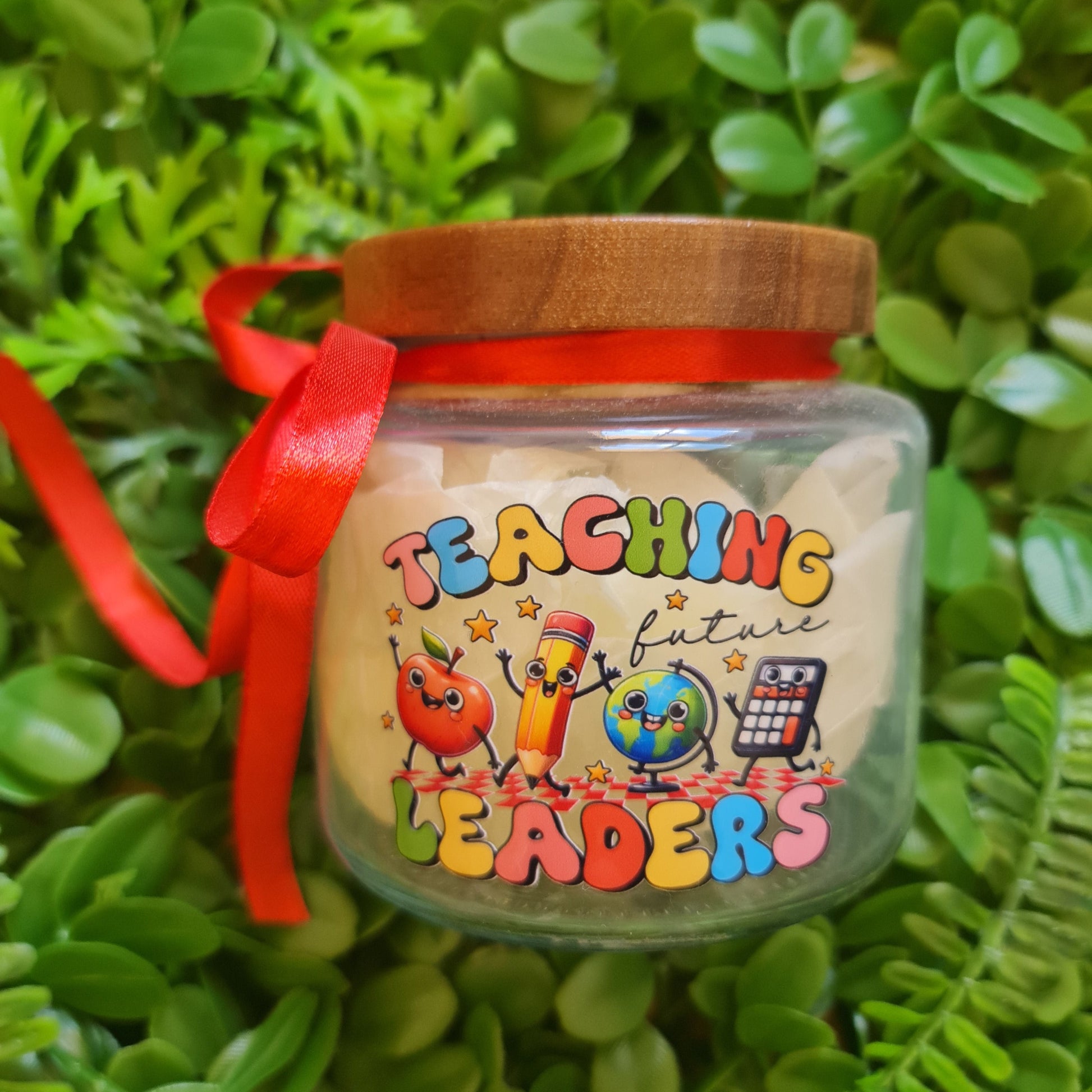 Small jar with colorful text and cartoon characters on a green leafy background